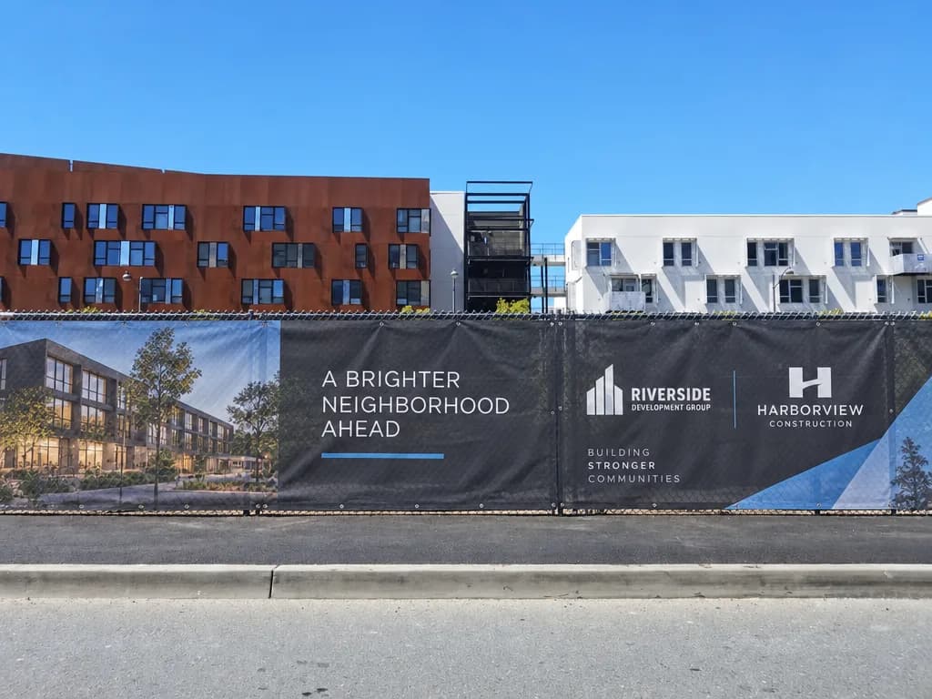 Apartment buildings under construction behind a fenced site